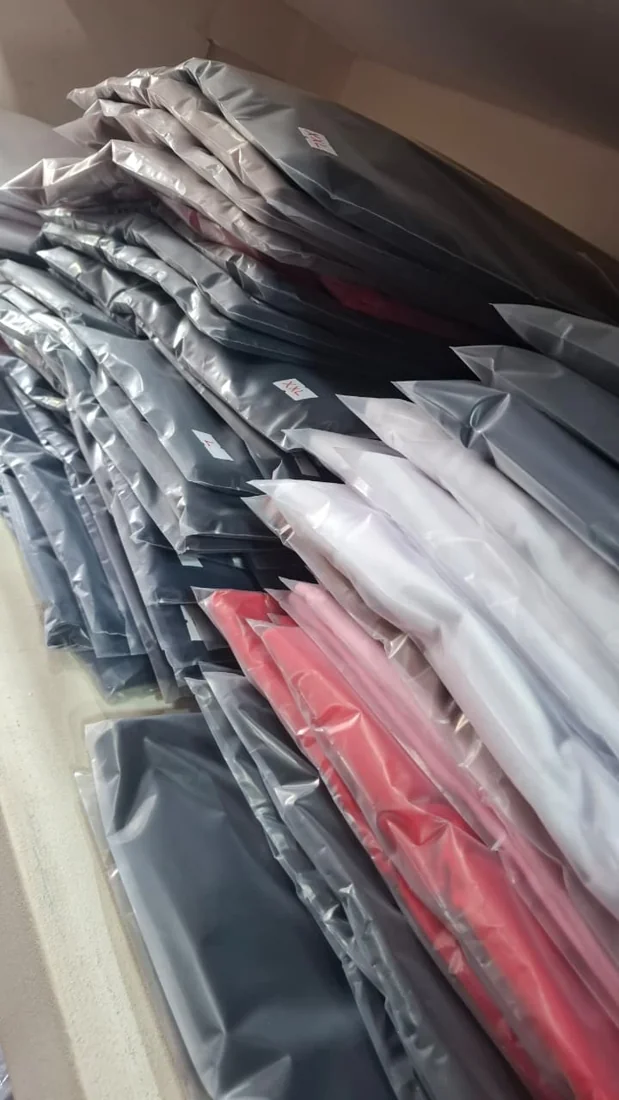 Foto real de remeras dobladas y embolsadas en el local